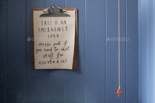 Close up of clipboard with emergency cord instructions on blue wall.