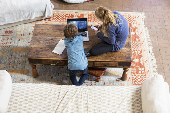 overhead view of teenage girl and her younger brother using laptop and smart phone