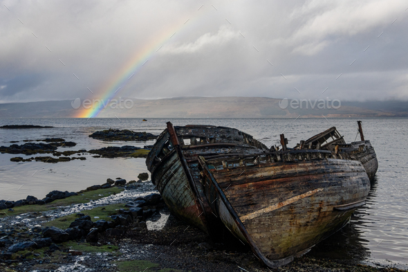 Rainbow and beached old wooden fishing boats on shore at Salen