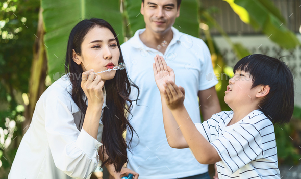 Asian family include father, mother and son playing the bubbles by blowing in happiness - Stock Photo - Images