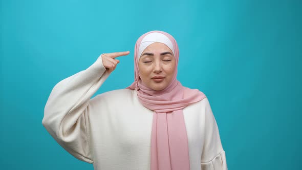 Displeased Annoyed Young Muslim Woman in Hijab Showing Stupid Gesture Accusing Crazy Cuckoo Mind