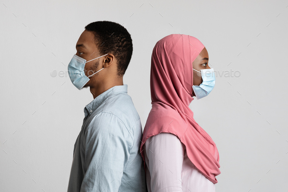 Muslim black couple in face masks standing back to back