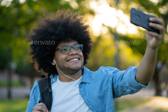 Latin man taking a selfie with phone outdoors.