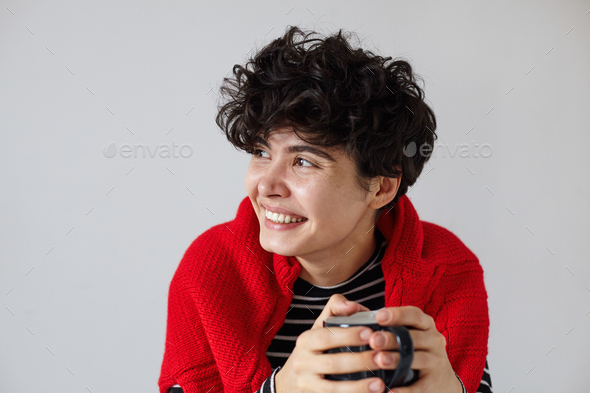 Close-up of young cheerful pretty short haired curly brunette lady looking happily - Stock Photo - Images