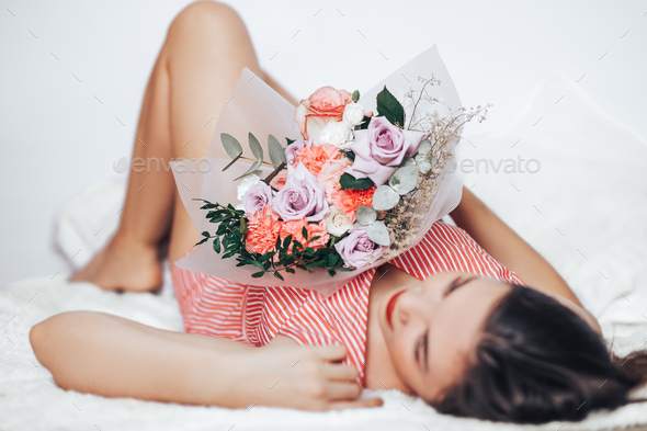 A woman holding a large mix of a bouquet of different flowers in her hands - Stock Photo - Images