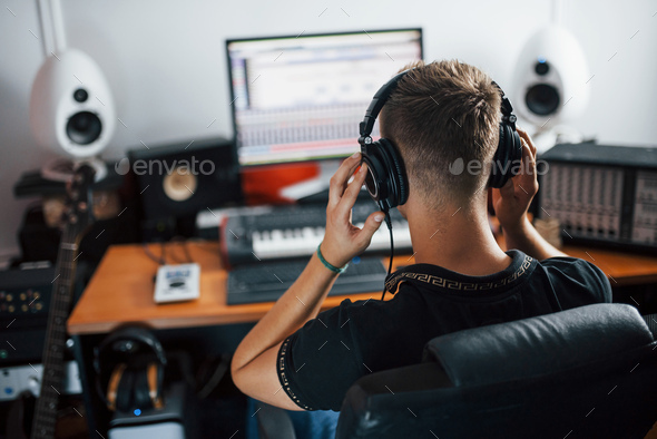 Listening to the music. Sound engineer in headphones working and mixing indoors in the studio - Stock Photo - Images