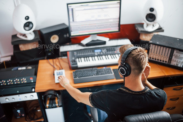 Concentrated at job. Sound engineer in headphones working and mixing music indoors in the studio - Stock Photo - Images