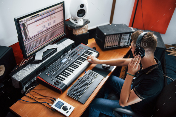 Sound engineer in headphones working and mixing music indoors in the studio - Stock Photo - Images