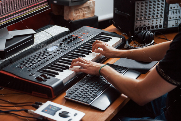 Playing midi keyboard. Sound engineer working and mixing music indoors in the studio - Stock Photo - Images