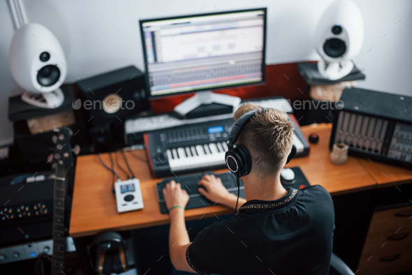 Sound engineer in headphones working and mixing music indoors in the studio - Stock Photo - Images