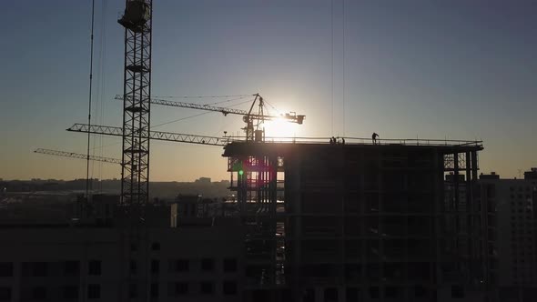 Construction Site at Sunset. Silhouette of a Construction Crane Near the Building