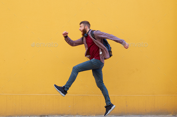 Young attractive ginger bearded man jumping, very fast running, late for work
