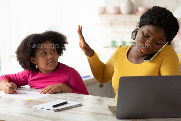 Busy Working African American Mother Ignoring Her Little Daughter Asking For Attention