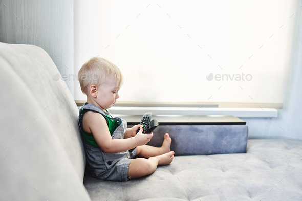 A little boy spends time at home playing with the remote control