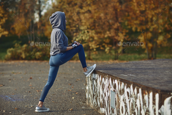 A girl in a tracksuit performs morning sports exercises on the street