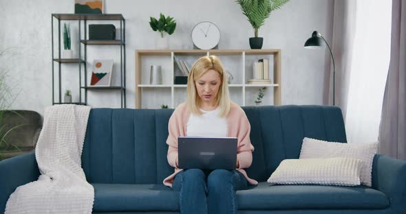 Woman Sitting at Home and Working on Laptop and Her Cheerful Smiling Active Kids Jumping alt