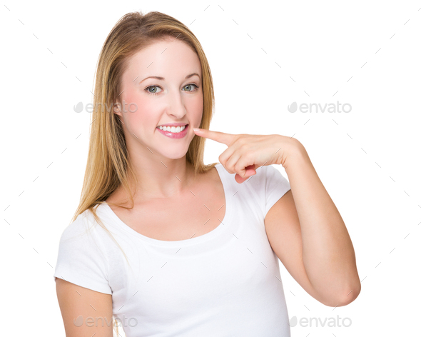 Caucasian woman with finger point to her teeth