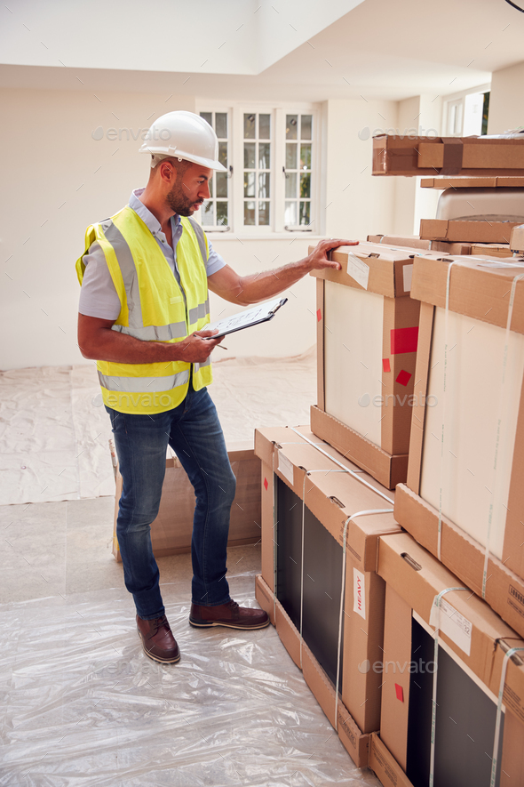 Builder Wearing Hard Hat With Clipboard Checking Delivery Of New Kitchen Units Inside Property - Stock Photo - Images