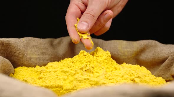 Human hand takes a pinch of a turmeric (curcuma) powder in a sac