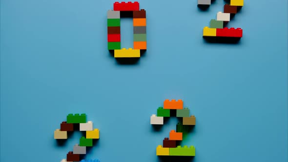Stop Motion of Making Symbol 2022 From Colorful Constructor Blocks on Blue Background