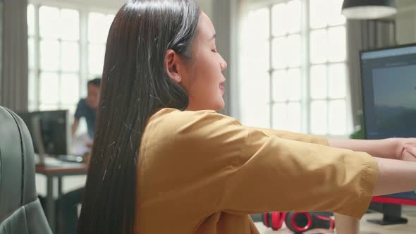 Female Video Editor Stretching While Works With Footage And Sound On Her Personal Computer In Office alt