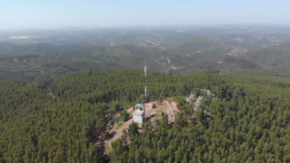Descending aerial shot of Telecommunication Radio Tower Mast surrounded by natural forest trees alt