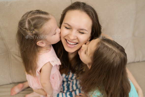 Two daughters kissing their mommy