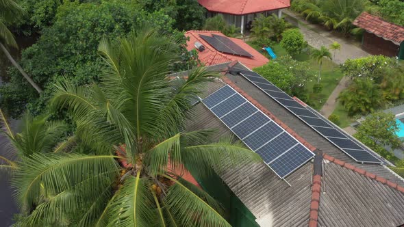 solar panels on the roof, palm trees near the house