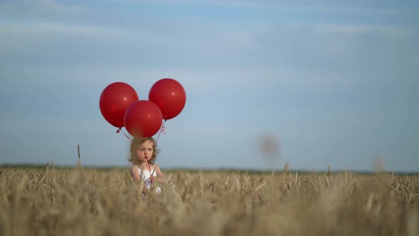 Happy Young Girl with Red Balloons in Wheat Field