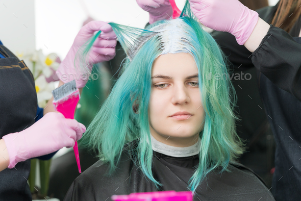 Two Hairdressers Combing Customers Hair Before Hair Dyeing Process. Back View of Woman Head