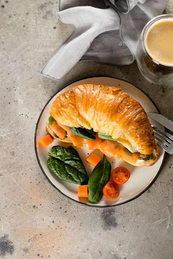 Croissant sandwich with salmon, spinach, glass of coffee. Healthy breakfast Photo by Anikona