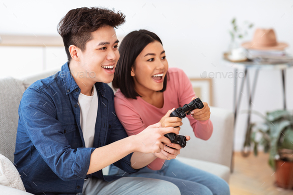 Asian man fun playing video games console with his girlfriend