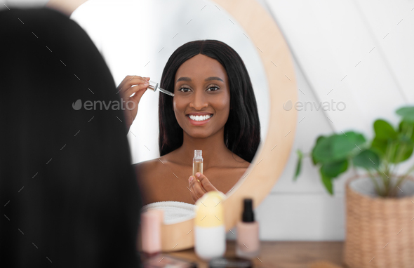 Cosmetology and spa. Smiling millennial african american lady hold pipette with cosmetic oil