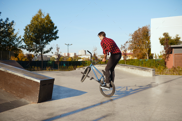Male bmx biker doing trick, training in skatepark