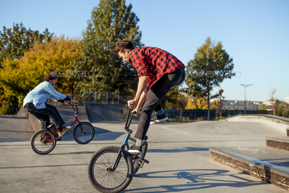 Two male bmx bikers doing tricks in skatepark