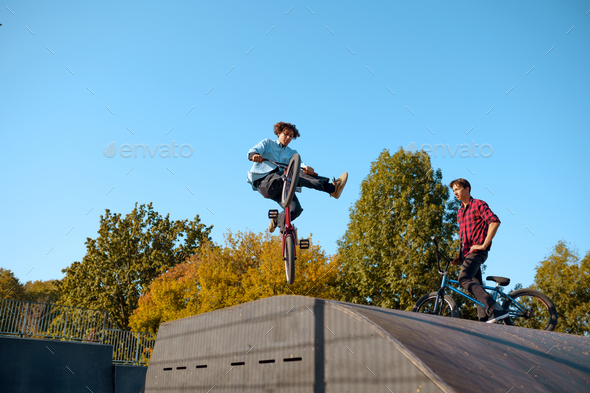Bmx bikers jumps on ramp, training in skatepark