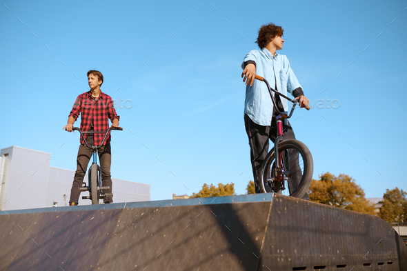Bmx biker standing on ramp, training in skatepark
