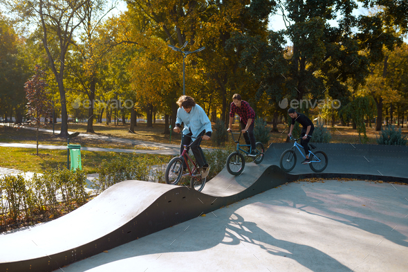 Three bmx riders on bikes, training in skatepark