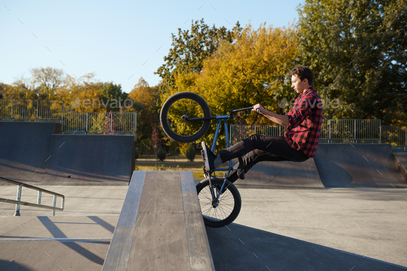 Young male bmx biker jumps on the wall