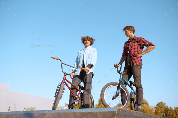 Bmx bikers, teenagers poses on ramp in skatepark