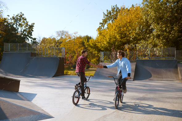 Two bmx bikers, training on ramp in skatepark