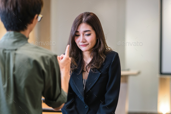 Reaw view of Furious boss scolding asian young businesswoman in formal suit by point