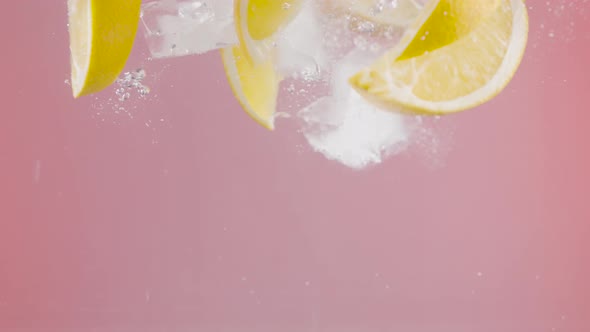 Lemon slices with ice fall into water alt