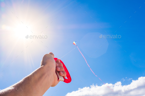 close up and portraitof hand holding a flying kite in the blue sky - freedom lifestyle and concept - Stock Photo - Images