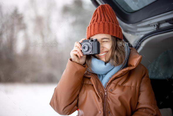Woman with old camera smiling and sitting in car trunk