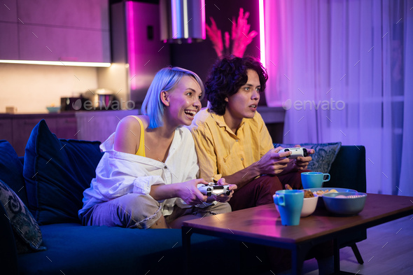 Handsome young man teaching how to play the video games to his girlfriend, on the couch, concept