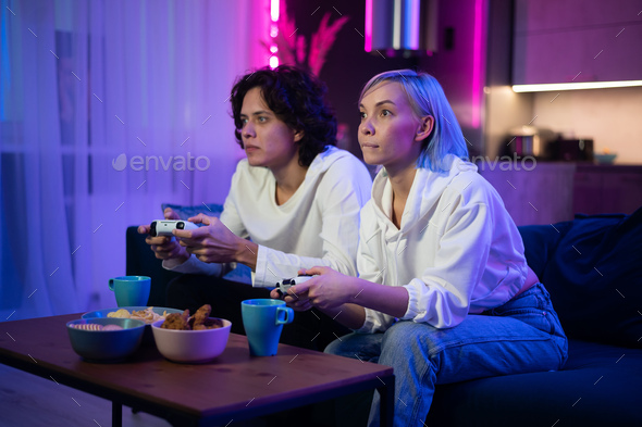 Photo of young couple playing video games at home at night