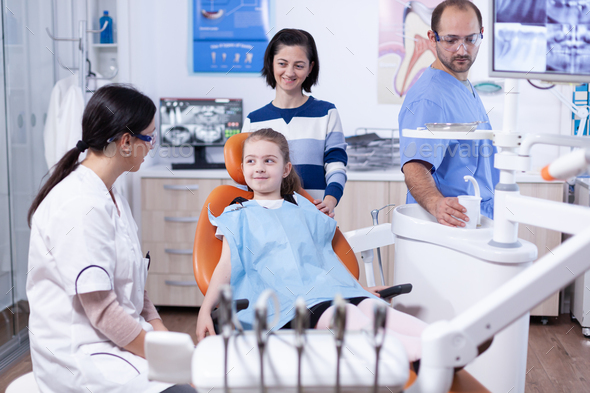 Happy little girl at pediatric dentist wearing dental bib