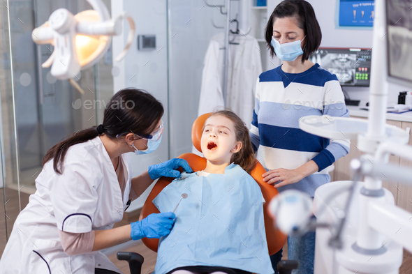 Dentist doing teeth check up of little girl