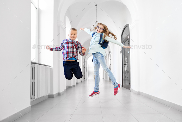 Happy schoolchildren posing, jumping in school